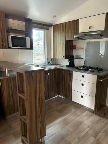 a kitchen with wooden cabinets and a counter top at Camping les Cigales - Mobil-home 4/6 personnes in Le Muy