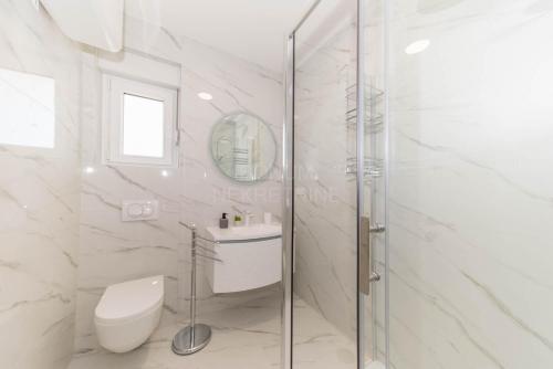e bagno bianco con servizi igienici e doccia in vetro. di Villa Adriatic Sunset a Jadrija