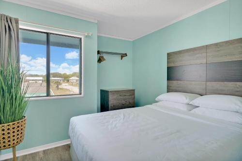 a bedroom with a large white bed and a window at Admiral's Quarters in Kure Beach
