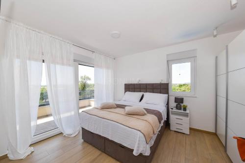 a white bedroom with a large bed and windows at Villa Adriatic Sunset in Jadrija