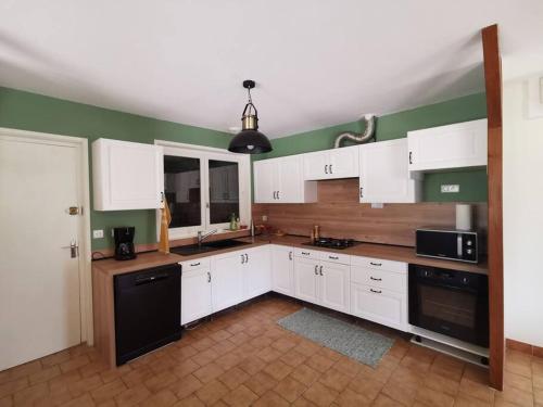 a kitchen with white cabinets and a black dishwasher at Calme entre pins et océan in Onesse-et-Laharie