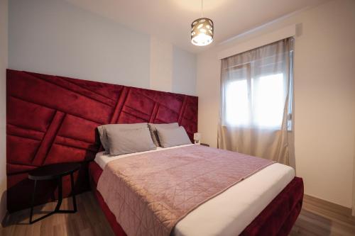 a bedroom with a large bed with a red headboard at Boutique Apartments Blitz in Bibinje