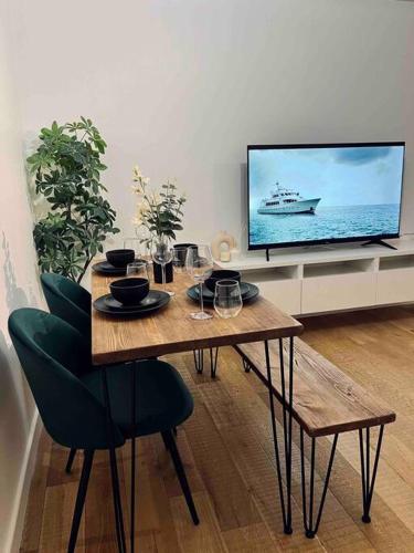 une salle à manger avec une table et une télévision dans l'établissement Lovely 1 Bed, Northolt Station, à Northolt