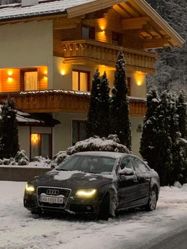 a car parked in the snow in front of a house at Ferienwohnung Marianne in Annaberg im Lammertal