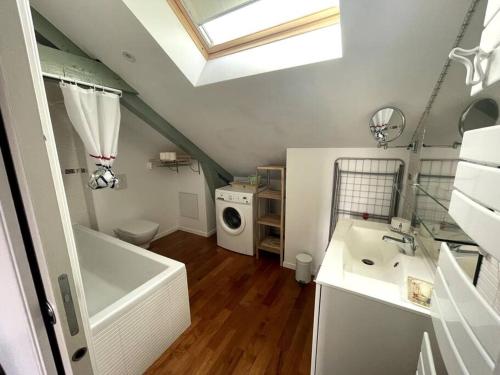 La salle de bains est pourvue d'une baignoire, d'un lavabo et d'un lave-linge. dans l'établissement Les Petits Loups - Accès parc - Stationnement gratuit, à Bagnères-de-Bigorre