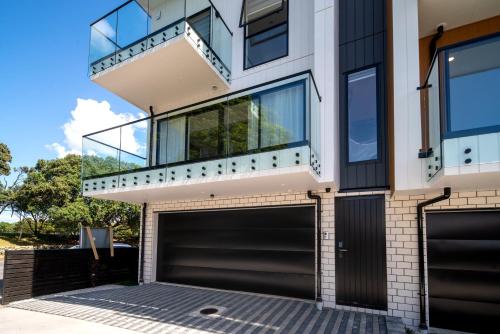 a house with two garage doors and a balcony at Luxury Brand New Designer Living in Auckland