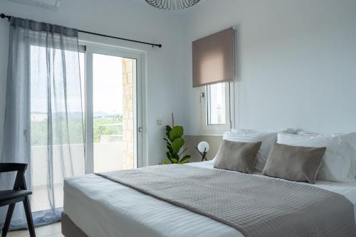 um quarto branco com uma cama grande e uma janela em Ros Solis Luxure House em Chania
