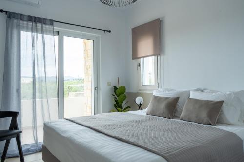 une chambre blanche avec un grand lit et une fenêtre dans l'établissement Ros Solis Luxure House, à La Canée