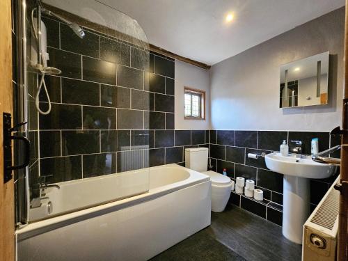 uma casa de banho com uma banheira, um WC e um lavatório. em Perfectly Located Pretty Cottage em Diss