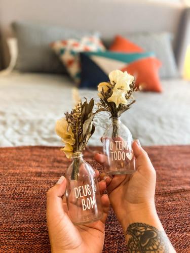 a person holding a bottle with flowers in it at VISTA MAR BOA VIAGEM - BEACH CLASS EXECUTIVE in Recife