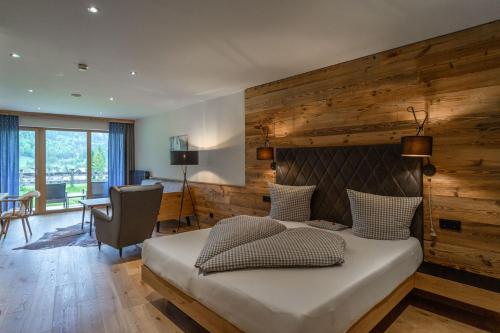 a bedroom with a large bed with a wooden wall at Hotel Landhaus Tirolerherz in Sankt Ulrich am Pillersee