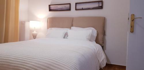 a bedroom with a white bed with two pictures on the wall at Comfy apartment in Athens