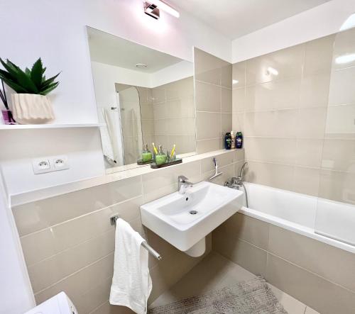 a white bathroom with a sink and a bath tub at Riverside luxury apartment in Bratislava