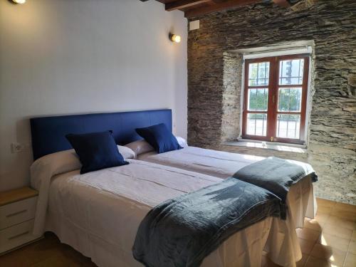 1 dormitorio con 1 cama con cabecero azul y ventana en LA GALLEGA, en Valdoviño