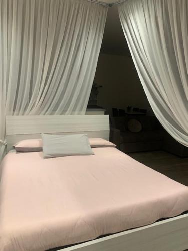 Una cama blanca con cortinas blancas en un dormitorio en Vecchie Mura G, en Santo Stefano di Magra