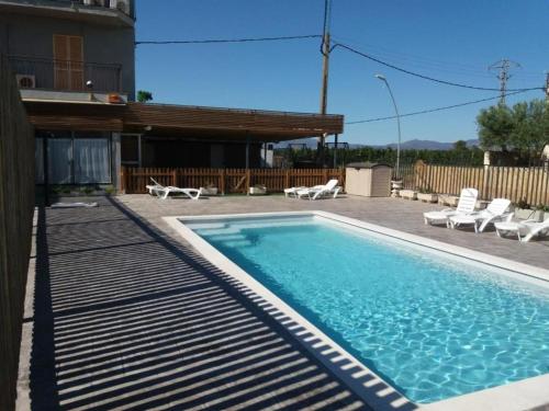 una piscina con tumbonas junto a una casa en La Masia BG parc en Sant Pere Pescador