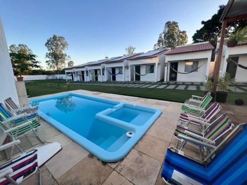 - une piscine avec 2 chaises et une maison dans l'établissement Pousada Mangaba, à Barreirinhas