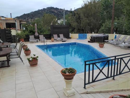 a swimming pool on a patio with chairs and a grill at Villa Mandarin Grove Alyanoe in Fodele