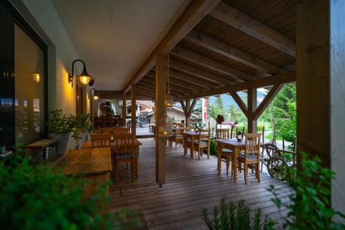 ザンクト・ウルリッヒ・アム・ピラーゼーにあるHotel Landhaus Tirolerherzの木製テーブルと椅子付きのデッキを併設するレストラン
