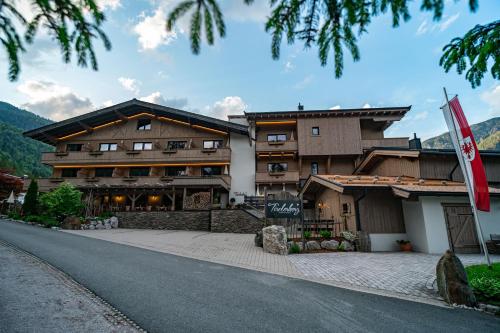 a building on a road with a flag in front of it at Hotel Landhaus Tirolerherz in Sankt Ulrich am Pillersee