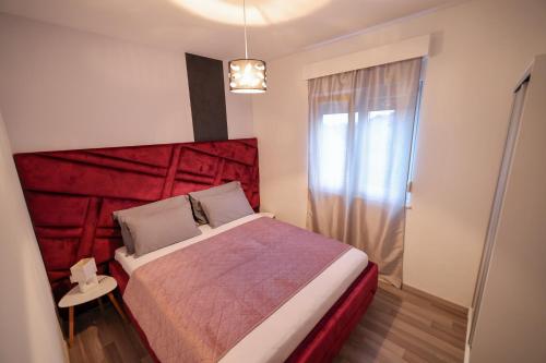 a bedroom with a bed with a red head board at Boutique Apartments Blitz in Bibinje