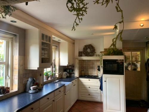 uma cozinha com armários brancos e bancadas azuis em B&B Erve Möskert em Geesteren