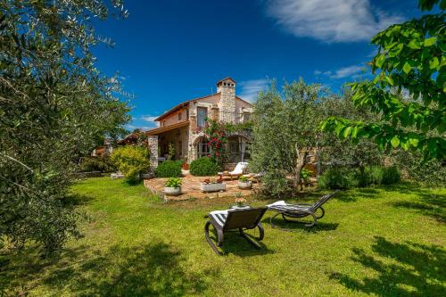 a yard with two chairs and a house at Holiday Home Eufemia in Svetvinčenat