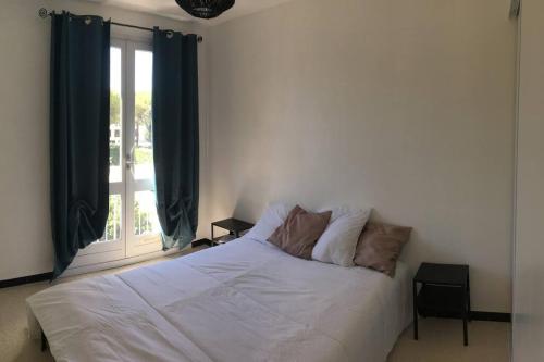- un lit blanc dans une chambre avec fenêtre dans l'établissement T2 très agréable et proche de la mer, à La Grande Motte