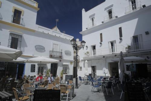 una cafetería al aire libre con mesas y sillas y edificios blancos en Wake up in Tarifa Hostel & Restaurant Lounge en Tarifa