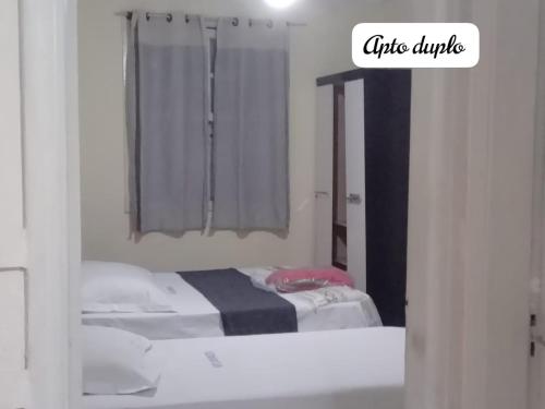 a bedroom with two beds and a window with curtains at Hospedaria Monumento in Sao Paulo