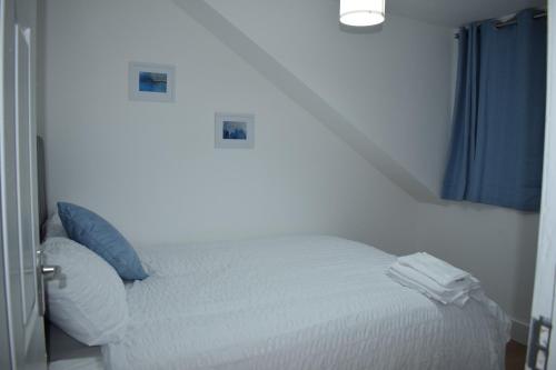 1 dormitorio con cama blanca y cortina azul en Forest Gate Haven, en Londres