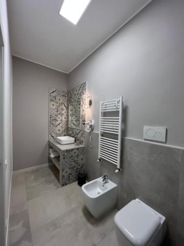 La salle de bains est pourvue de toilettes blanches et d'un lavabo. dans l'établissement Stanze d’Autore, à Tarente