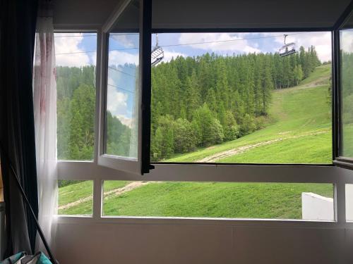 una ventana abierta con vistas a un campo verde en Studio Puy saint vincent 1600 en Les Prés