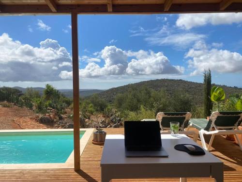 a laptop computer sitting on a table next to a pool at Eco-Villa Monte Do Barrocalinho in Loulé