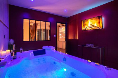 une grande salle de bains avec une grande baignoire à éclairage violet dans l'établissement Spa & Détente - Cinéma - Parking - Gare, à Amiens