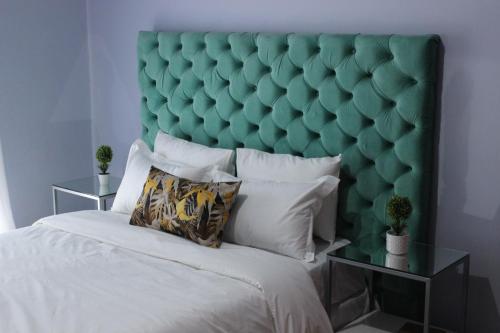 a bed with a green padded headboard in a bedroom at Blue Agave MH in Lusaka