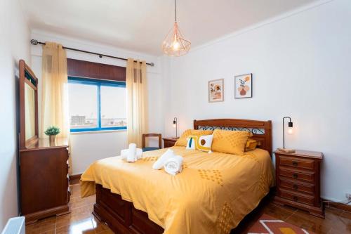 een slaapkamer met een bed met gele lakens en een raam bij Casa conde - Blue coast in Setúbal