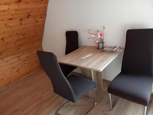 einen Holztisch mit zwei Stühlen und eine Vase mit Blumen in der Unterkunft Ferienwohnung Ravensburg in Ravensburg