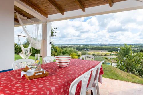 a red table and chairs on a patio with a view at Monte Cerro da Vigia by Vacationy in Zambujeira do Mar