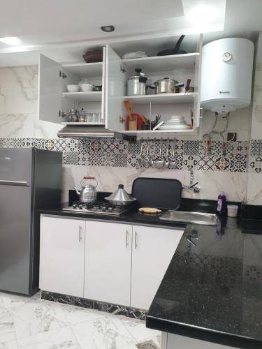 a kitchen with white cabinets and a black counter top at White House in Azrou