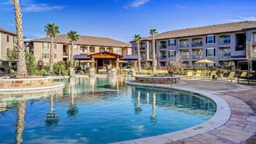 a swimming pool at a resort with palm trees and buildings at Emerald City Luxury Suite ~Fully Gated Community in Midland