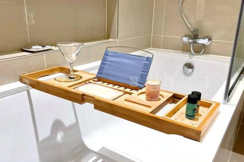 a wooden tray sitting on a bath tub with a wine glass at The Shrashi Suites, Dubai Creek Harbour - Paradise on the Island with Dubai Skyline & Burj Khaleefa View in Dubai