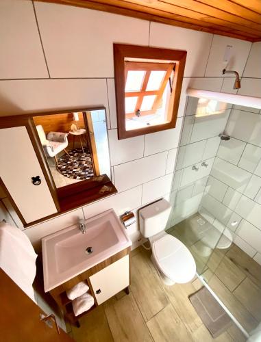 uma casa de banho com um lavatório, um WC e um espelho. em Chalés da Serra em São Francisco de Paula