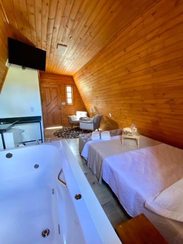a bedroom with two beds and a tub in a room at Chalés da Serra in São Francisco de Paula
