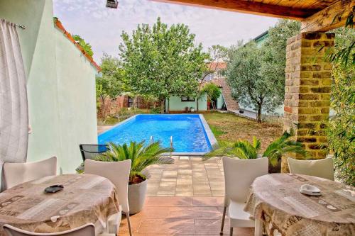 un patio al aire libre con mesas y una piscina en Radeki polje 50, en Loborika