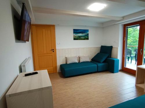 een woonkamer met een blauwe bank en een tv bij Siesta apartment Bled in Bled