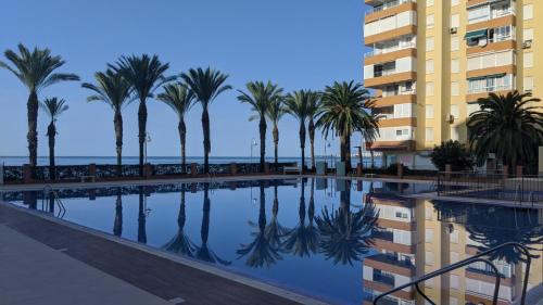 una piscina con palme e un edificio di VISTA PLAYA a Algarrobo-Costa