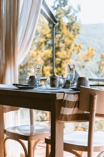 a table with plates and glasses and a window at Arrayan Lake View Mountain Lodge & Casa De Te Arrayan in San Martín de los Andes