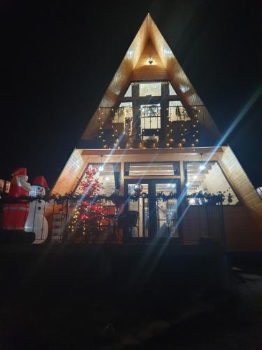 a log cabin with a christmas tree and lights at Cabana de Vis Valea Prahovei - ciubăr și saună la munte in Talea