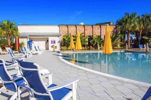 a swimming pool with chairs and umbrellas at Pool Home Champions Gate Area with Resort Amenities Next to Disney in Davenport